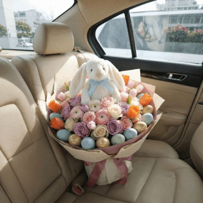 Pastel Easter bouquet with roses, tulips, decorative eggs, and a plush bunny in soft spring colours