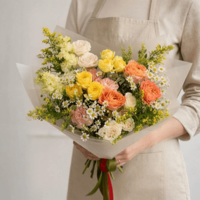 Mother’s Day bouquet with yellow, peach, and white flowers in a natural garden-style arrangement