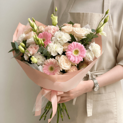 Mother’s Day bouquet with pink gerbera daisies, blush roses, and white flowers wrapped in soft pink paper