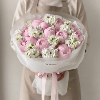 Soft pink peony bouquet with small white accent flowers wrapped in pale paper
