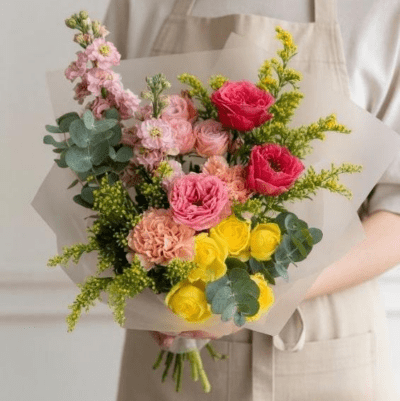 Bouquet with yellow roses, blush and pink flowers, eucalyptus, and soft greenery wrapped in neutral paper