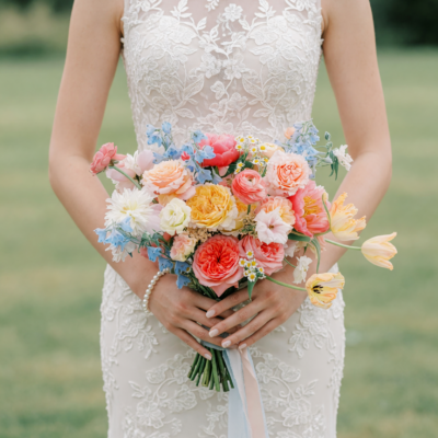 Bridal flowers bouquets with pastel garden roses, coral ranunculus, peach tulips, blue delphiniums, chamomile flowers, and romantic seasonal wedding blooms.
