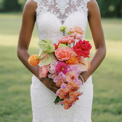 Popular wedding bouquets with cascading peach and pink orchids, coral roses and green flowers in a colourful bridal arrangement.