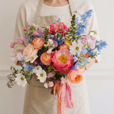 Bridal blooms with coral, peach, powder blue, pink and white flowers arranged as a romantic colourful wedding bouquet.