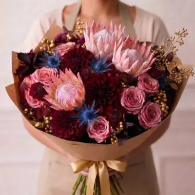 Luxury flowers Vancouver bouquet with pink protea, dusty pink roses, burgundy dahlias, blue accents and decorative gold details.