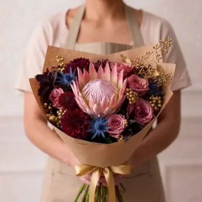 Luxury flowers Vancouver bouquet with pink protea, dusty pink roses, burgundy dahlias, blue accents and decorative gold details.