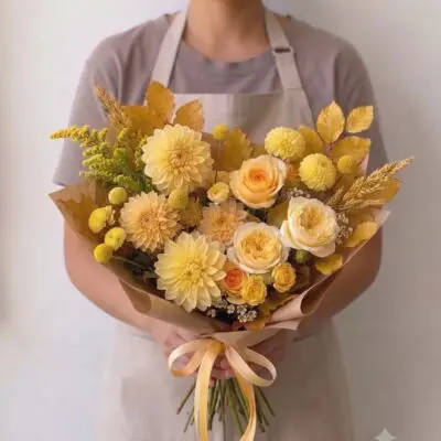 Yellow flowers Vancouver Butterscotch bouquet with cream and apricot roses, pale yellow dahlias, golden foliage and wheat-like accents.