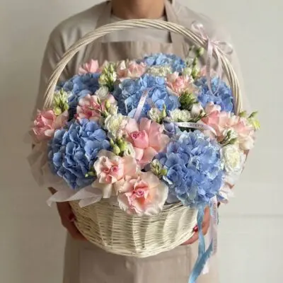 Hydrangea flower basket Vancouver with blue hydrangeas, blush pink roses and white flowers arranged in a light woven handled basket