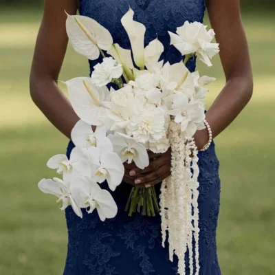White wedding bouquet with cascading orchids, calla lilies, anthuriums, carnations, hydrangeas, and trailing white amaranthus for an elegant bridal look.