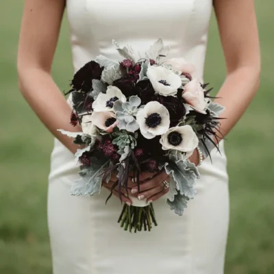 Popular wedding bouquets featuring an anemone wedding bouquet with white anemones, deep burgundy roses, dusty miller, and dramatic bridal flowers.