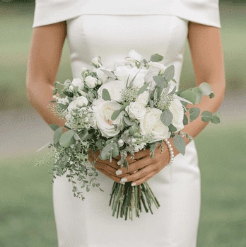 White wedding bouquet with white roses, lisianthus, eucalyptus, baby's breath, and fresh greenery in a hand-tied bridal arrangement.
