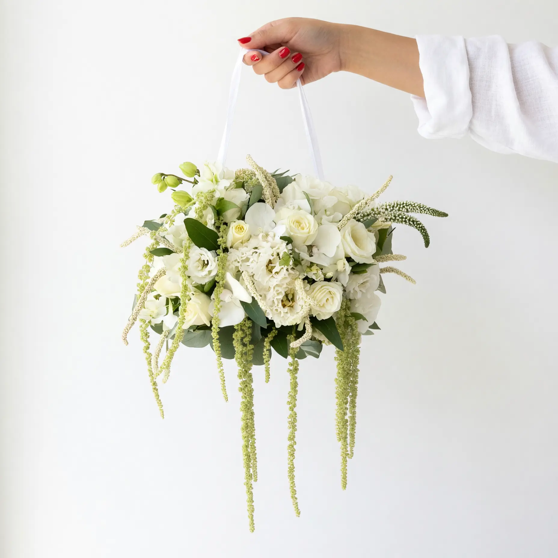 Ivory hanging floral basket with white roses, orchids, lisianthus, hydrangeas, eucalyptus, and cascading greenery for bridal flowers bouquets