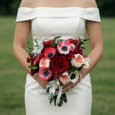 Red wedding bouquet with red roses, pink anemones, blush garden roses and dusty miller for elegant bridal wedding ceremony
