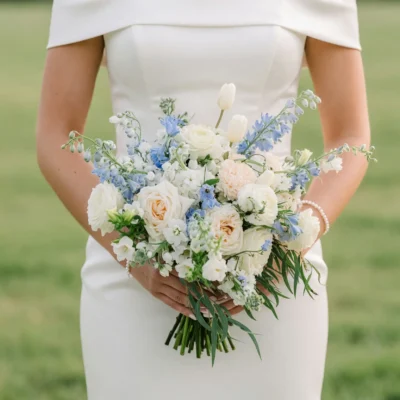 Beach Wedding Bouquets featuring ivory roses, peach blooms, white tulips, pale blue delphinium, delicate white flowers, and flowing greenery