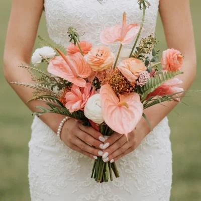 Beach Wedding Bouquets featuring peach anthuriums, apricot roses, orange pincushion protea-like blooms, white layered flowers, and tropical greenery