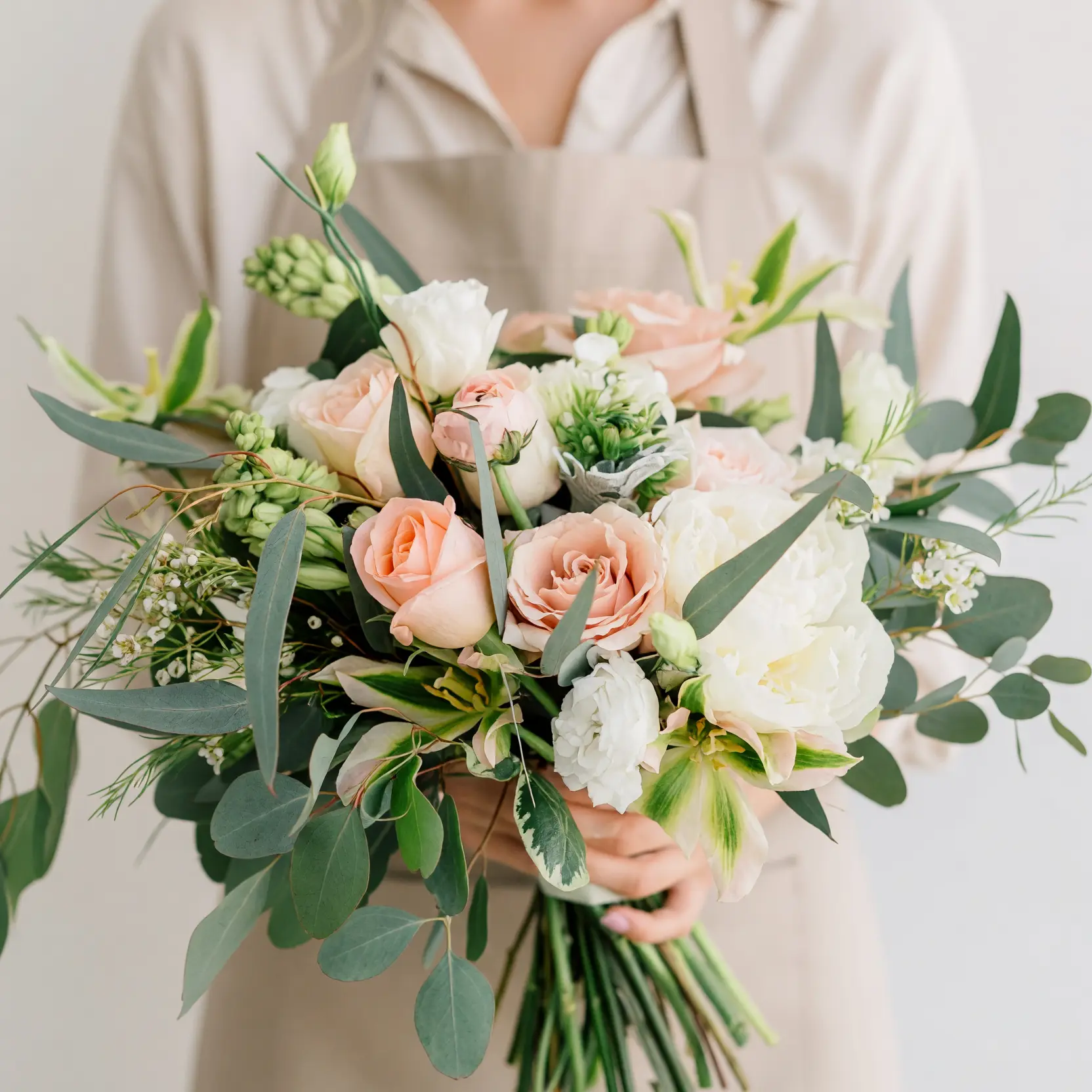 Beach Wedding Bouquets featuring peach anthuriums, apricot roses, orange pincushion protea-like blooms, white layered flowers, and tropical greenery