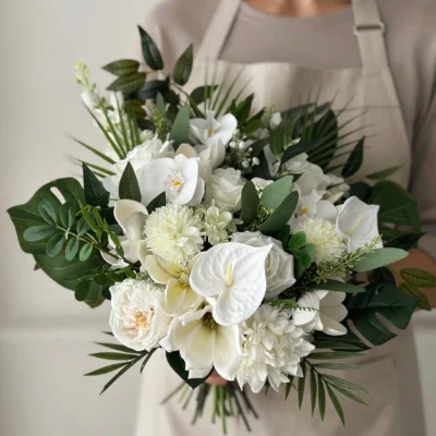 Beach Wedding Bouquets featuring white anthuriums, ivory roses, white orchids, ruffled white blooms, monstera leaves, and tropical palm foliage