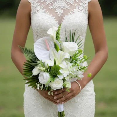 Beach Wedding Bouquets featuring a white anthurium, ivory calla lilies, white lilies, roses, layered blooms, green thistle-like texture, and palm foliage