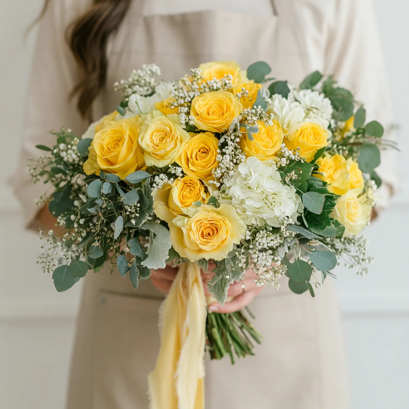 Yellow rose and white hydrangea wedding bouquet with baby’s breath, eucalyptus foliage, and flowing yellow ribbon.