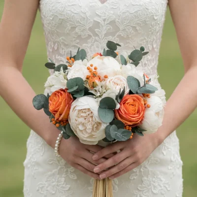 Orange Wedding Bouquets of warm orange roses, creamy peony-like blooms, orange berries and eucalyptus held by a bride