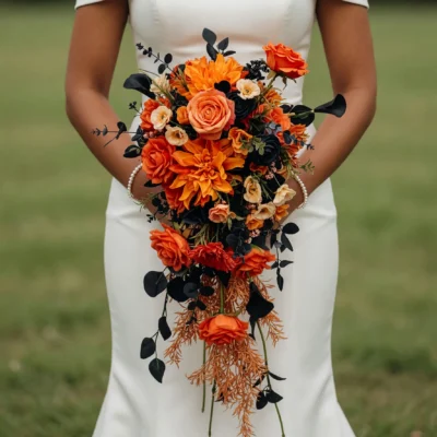 Orange Wedding Bouquets of vivid orange roses and dahlias, cream flowers, dark foliage and cascading bronze accents held by a bride