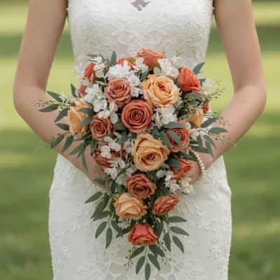 Orange Wedding Bouquets of toffee, peach and orange roses, white blossoms and cascading green foliage held by a bride