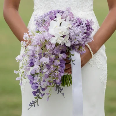 Purple Wedding Bouquets of cascading lilac blossoms, white orchid-like flowers and pale lavender ribbon held by a bride