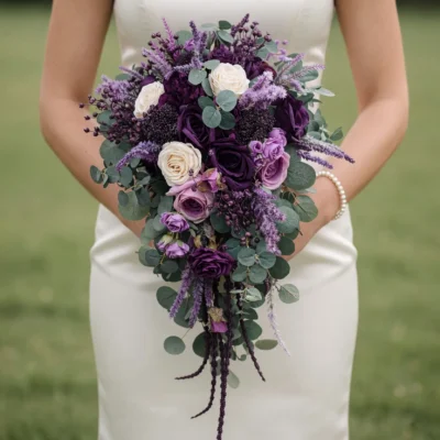 Purple Wedding Bouquets featuring plum and lavender roses, ivory blooms, eucalyptus, purple flower spikes, and a cascading bridal shape