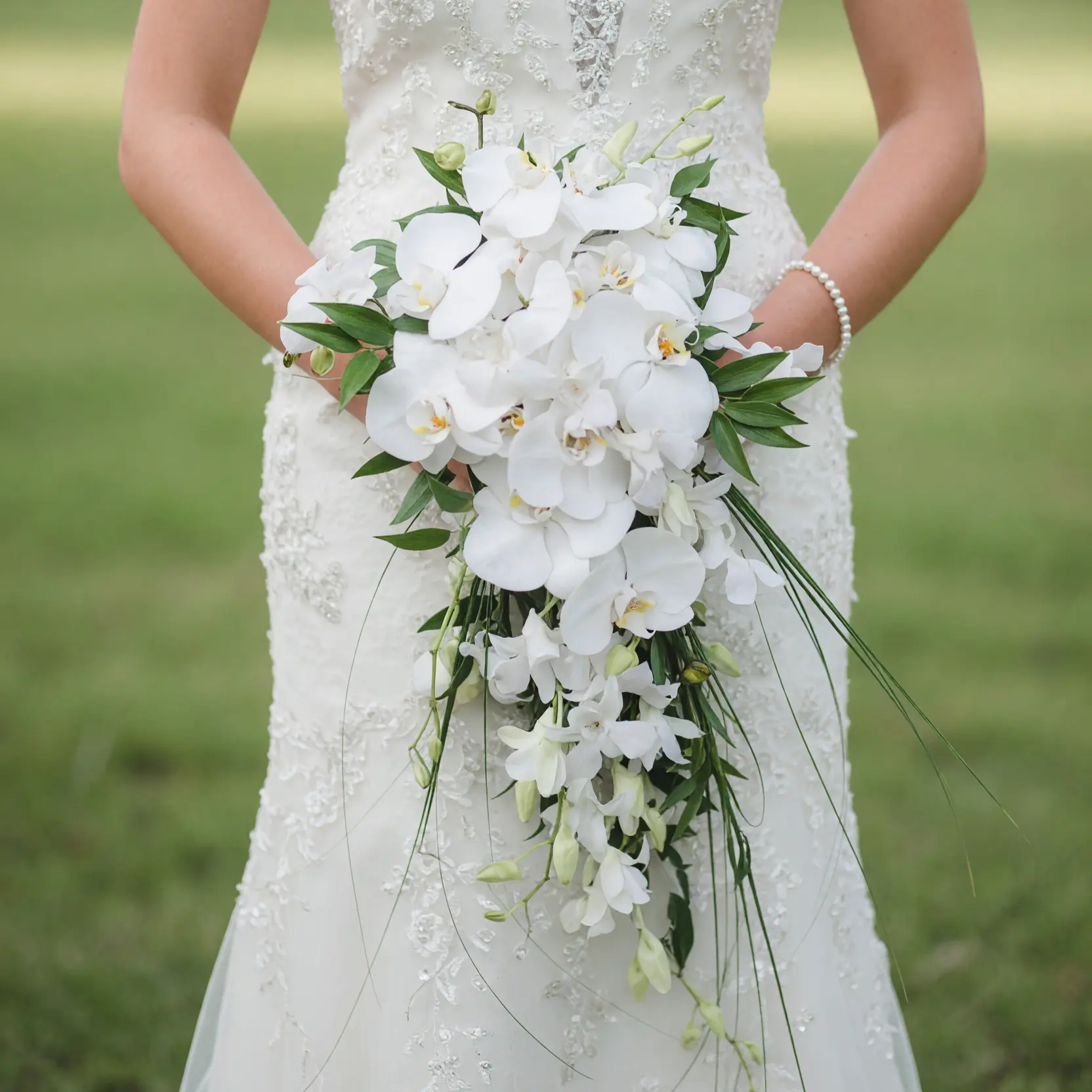 Bridal blooms featuring cascading white Phalaenopsis orchids, elegant greenery, and romantic orchid wedding bouquet for brides.