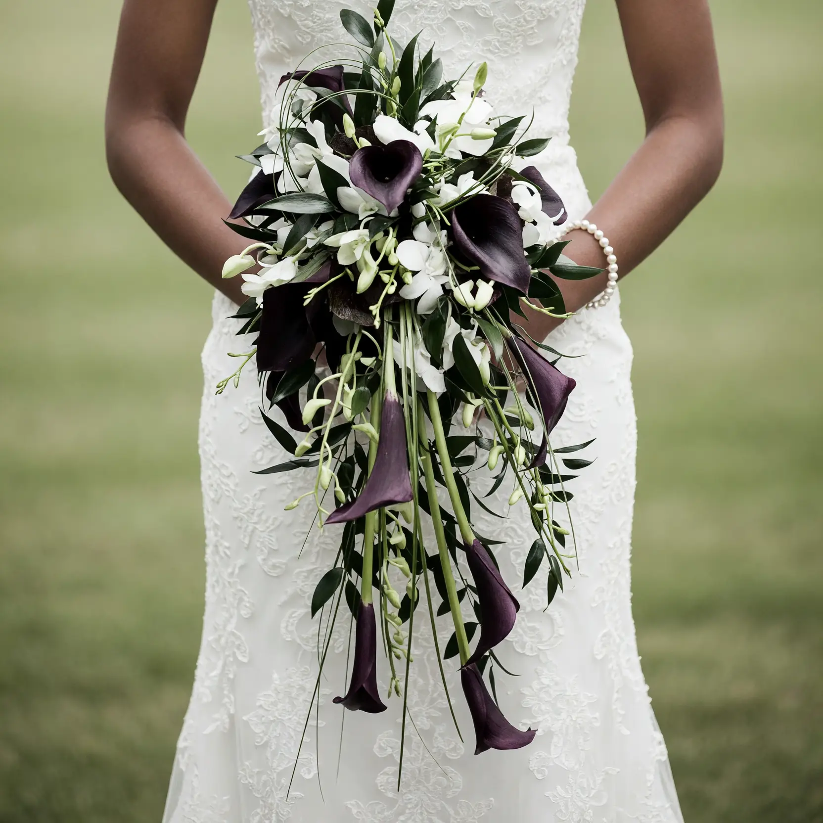 Bridal flowers bouquets with cascading dark calla lilies, white orchids, fresh greenery, and elegant modern wedding floral design.