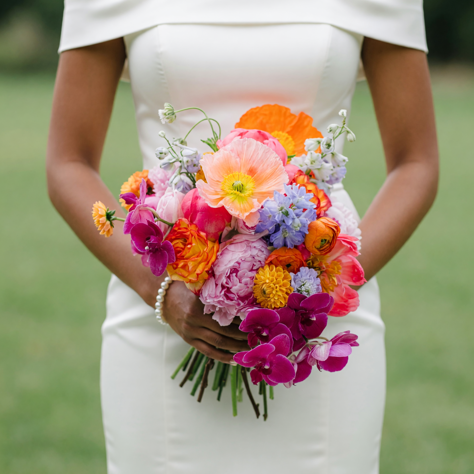 Bridal flowers bouquets featuring blush peonies, magenta orchids, orange poppies, ranunculus, tulips, blue delphiniums, and colourful seasonal wedding flowers