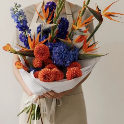 Bridal flowers bouquets with orange bird-of-paradise, blue flowers, and rust dahlias for a bold tropical wedding
