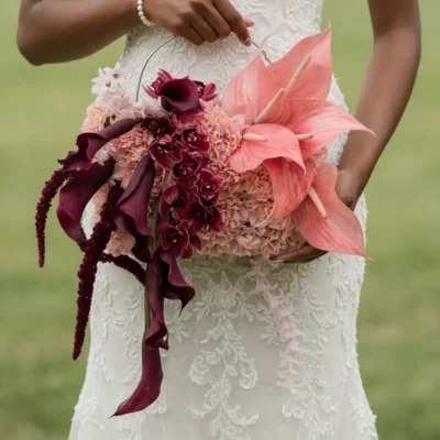Bridal flowers bouquets with blush pink anthuriums, burgundy calla lilies, soft hydrangeas, and cascading wine-colored blooms held by a bride in a lace wedding dress