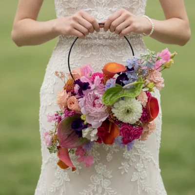 Popular wedding bouquets with colorful pink, coral, purple, blue, and red flowers arranged around a modern hoop for a bride