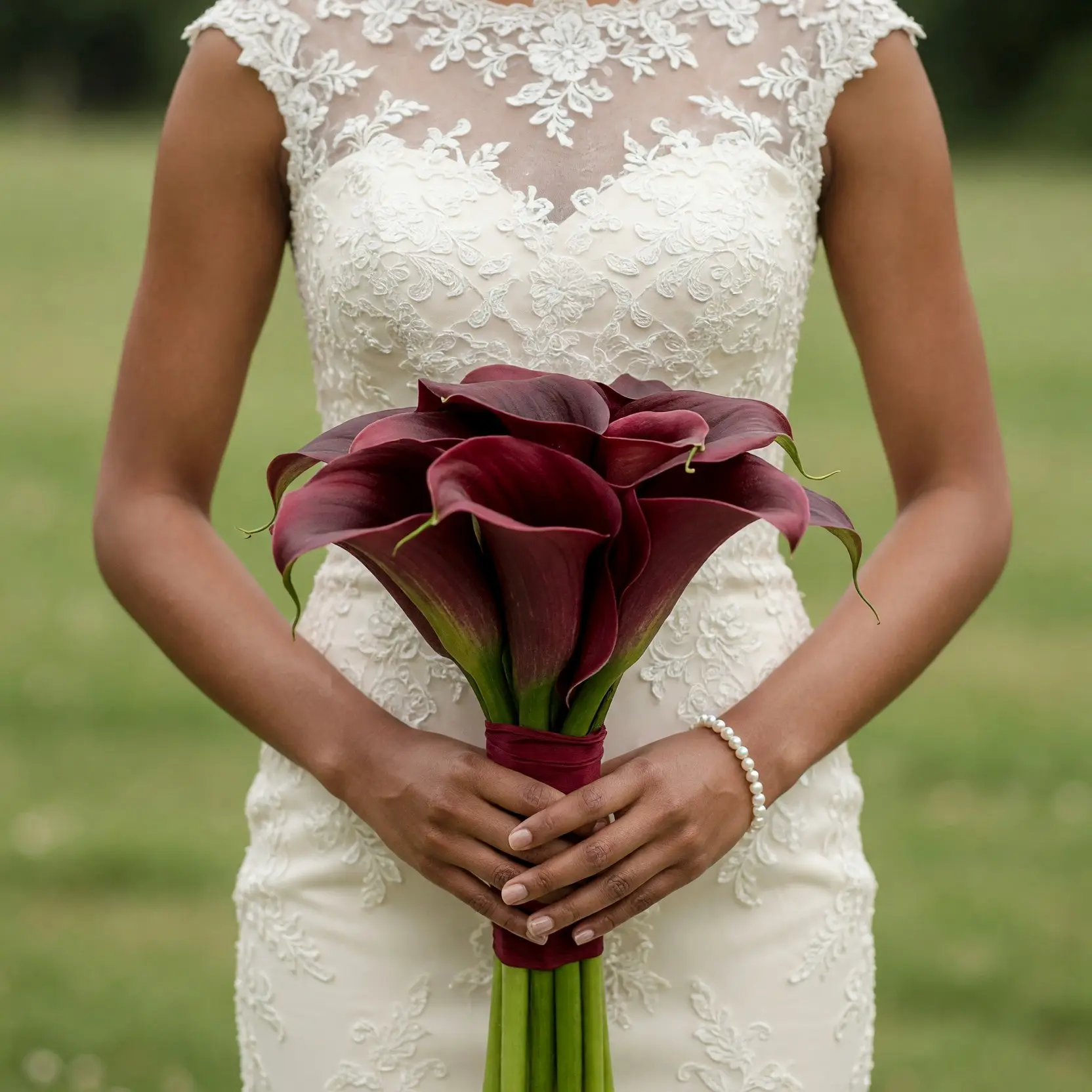 Burgundy calla lily wedding bouquet held by a bride in a white lace dress for elegant bridal flowers bouquets inspiration