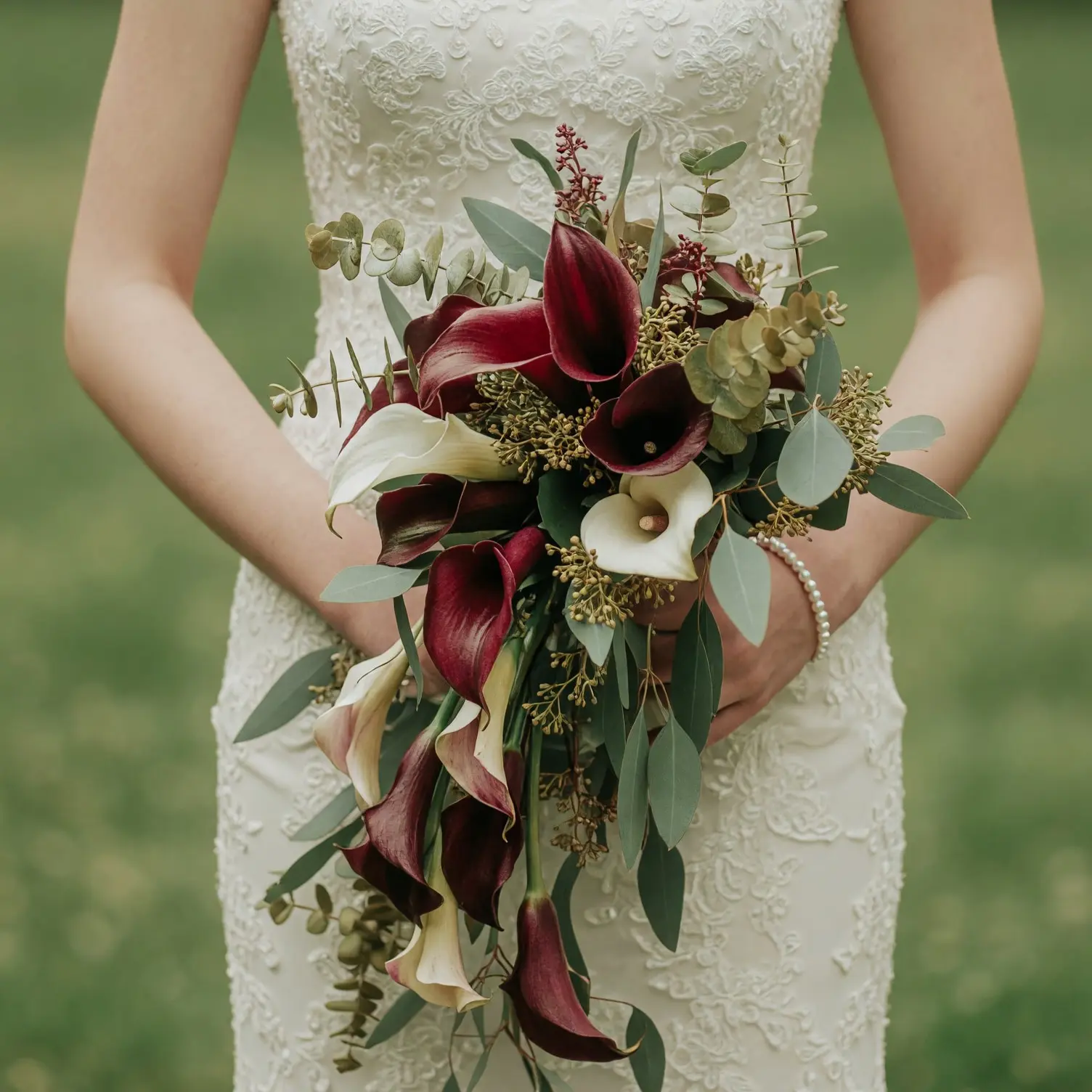 Burgundy calla lily wedding bouquet with ivory calla lilies, eucalyptus, dark green foliage, berry-like accents, and cascading flowers