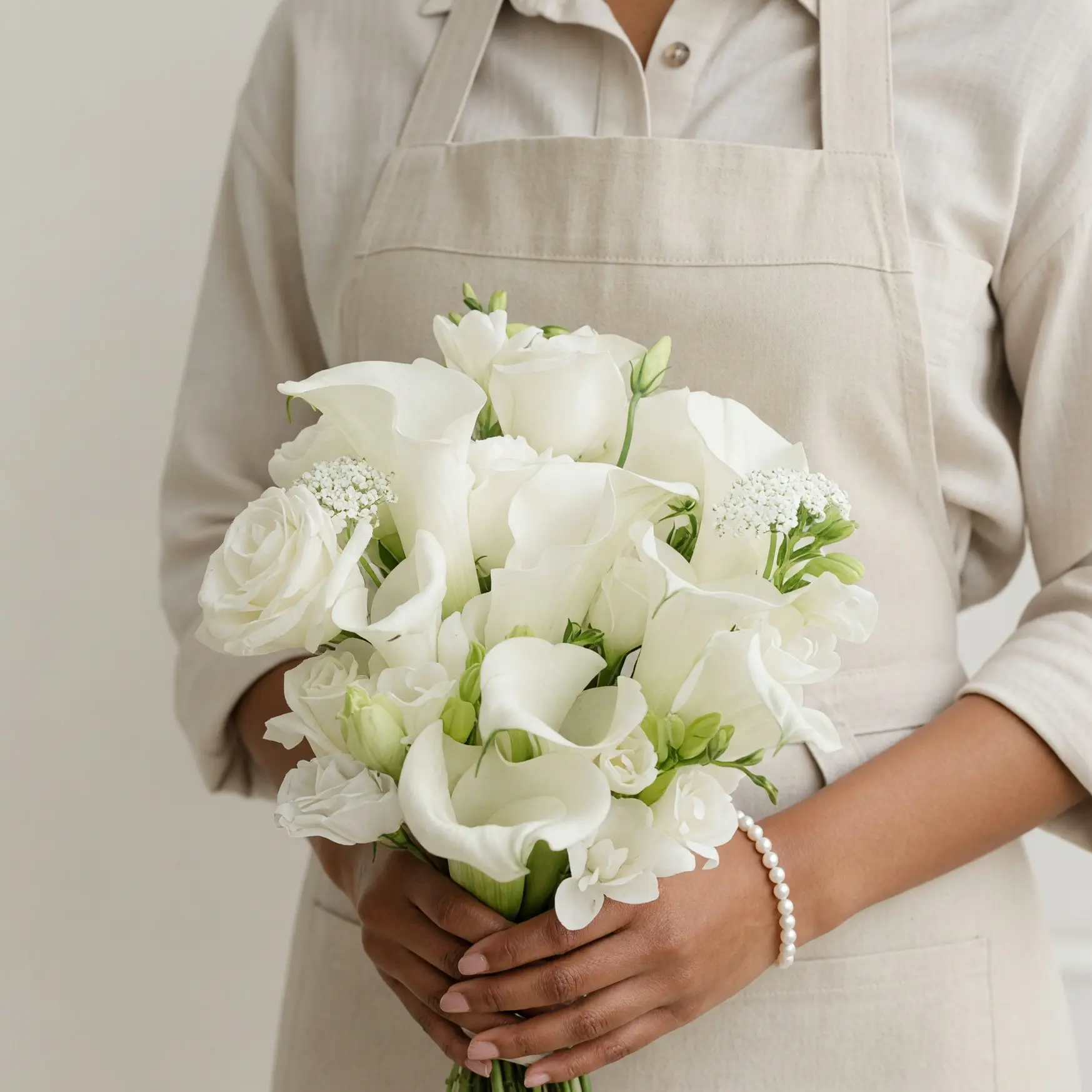 White calla lily bouquet with creamy roses, delicate white blossoms, lace-like filler flowers, and fresh green buds