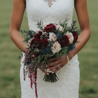 Christmas & Winter Wedding Bouquets boho style flowers with burgundy blooms, ivory roses, blue thistles, pinecones, eucalyptus and evergreen foliage