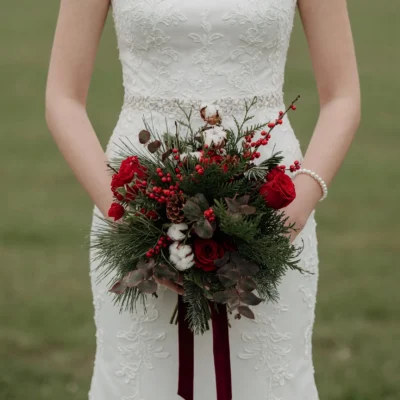 Popular wedding bouquets with red roses, berries, cotton, pinecones, eucalyptus and evergreen foliage for a winter bride