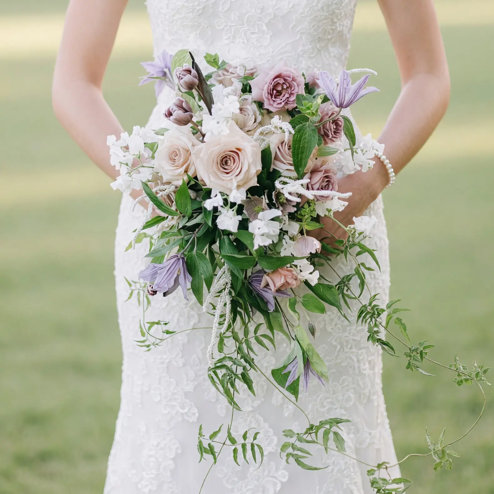 popular wedding bouquets with blush roses, ivory flowers, lavender blooms and cascading greenery held by a bride