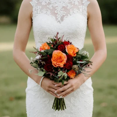 Fall bridal flowers bouquets with orange and burgundy roses, berries and greenery for an elegant autumn wedding