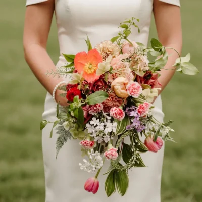 Bridal flowers bouquets with coral and blush flowers, red roses, white accents, and cascading greenery for a romantic fall wedding