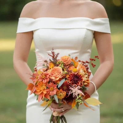 Bridal flowers bouquets with copper dahlias, peach roses, berry accents, pink textures, and autumn foliage for a romantic fall bride