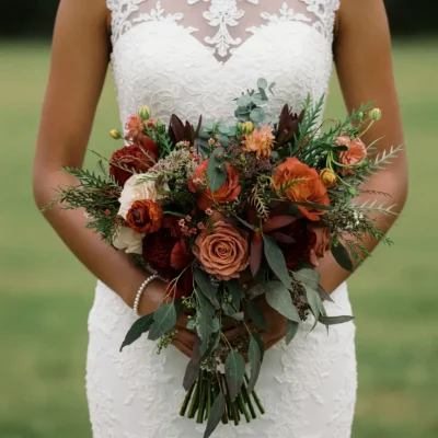 Bridal bouquet cost inspiration with copper roses, burgundy flowers, ivory blooms, eucalyptus, and woodland greenery for a romantic fall bride