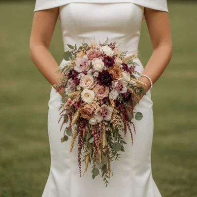 Bridal flowers bouquets with dusty rose and ivory flowers, burgundy accents, wheat, eucalyptus, and cascading greenery for a romantic fall bride