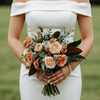 Popular wedding bouquets with caramel and ivory roses, magnolia leaves, thistle accents, eucalyptus, and textured greenery for an elegant fall bride