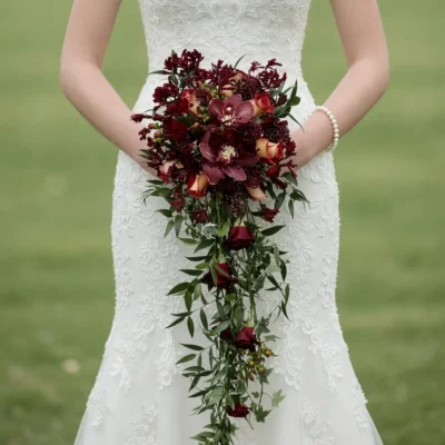 Bridal flowers bouquets with burgundy orchids, wine roses, dark berry accents, and long cascading green foliage for an elegant fall bride