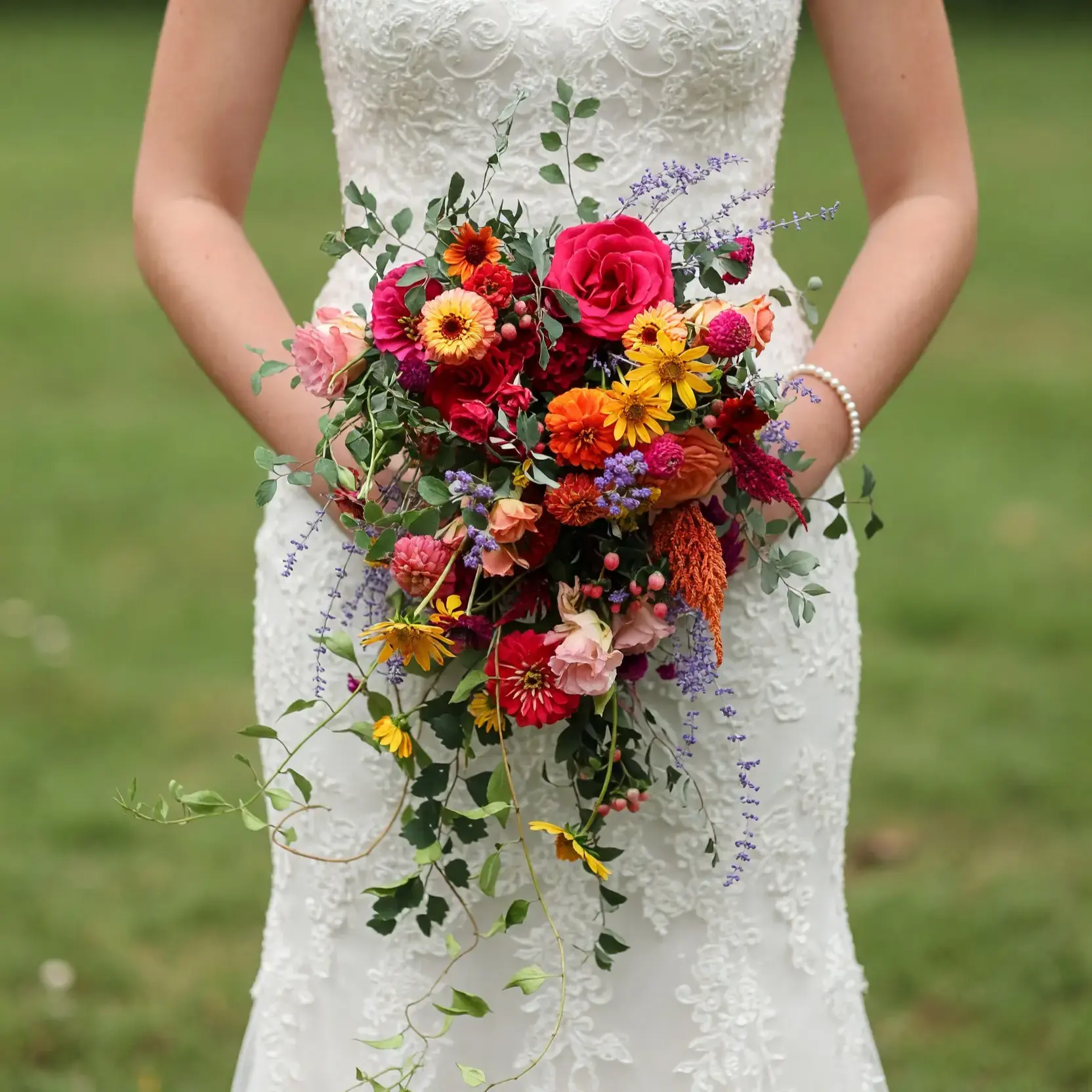 Bridal flowers bouquets with pink roses, orange and yellow wildflowers, lavender accents, berries, eucalyptus, and cascading greenery for a fall bride