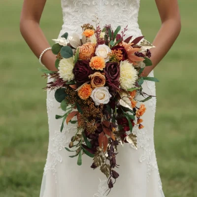 Bridal blooms with burgundy roses, ivory chrysanthemums, peach flowers, eucalyptus, bronze foliage, berries, and cascading greenery for a fall bride