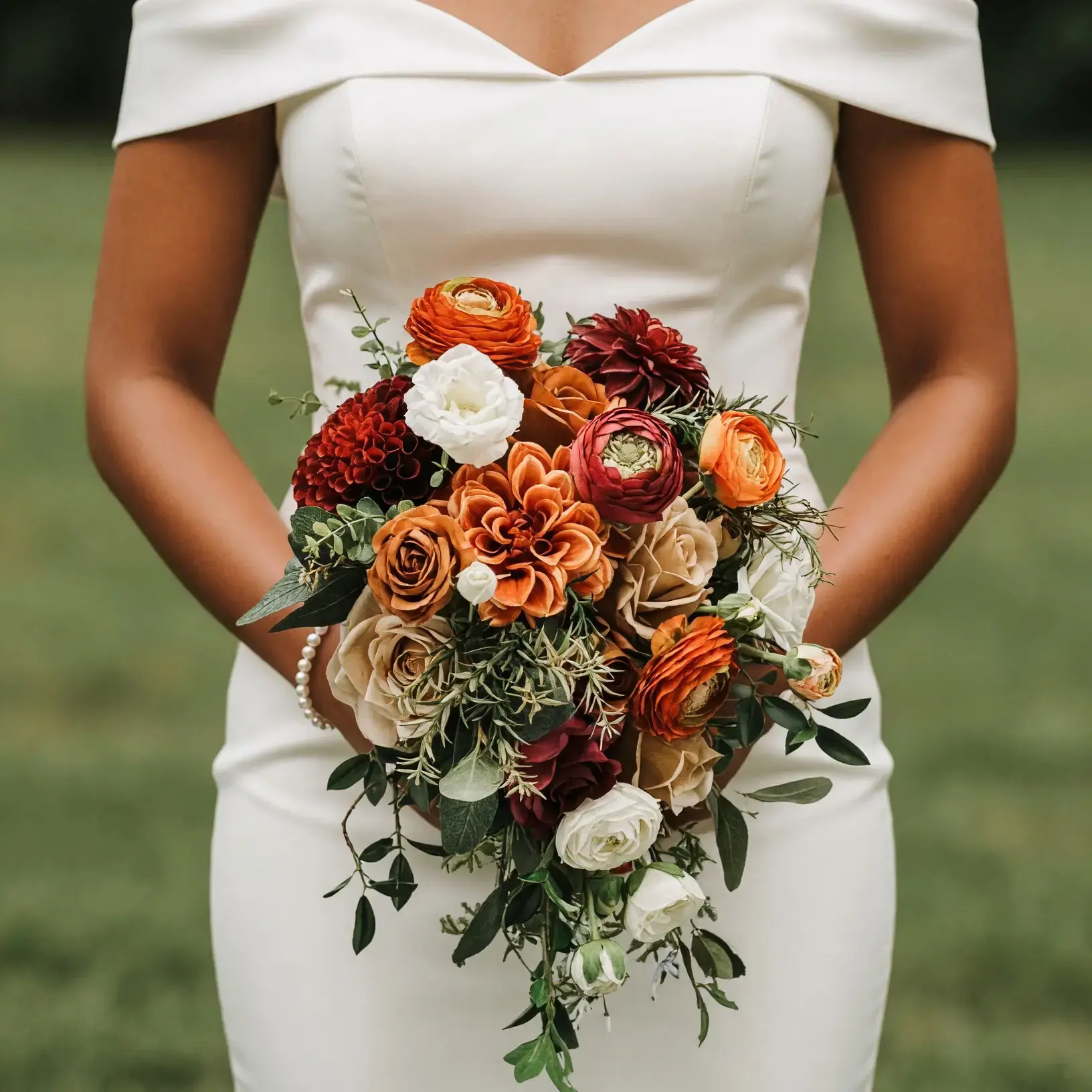 Bridal blooms with burnt-orange flowers, caramel roses, rust dahlias, ivory blooms, burgundy accents, and cascading greenery for a fall bride
